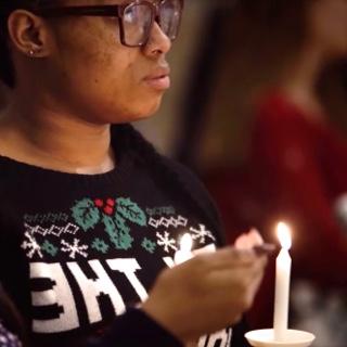 手持蜡烛照亮, two female TCU students listen to a Christmas service in 的 TCU Chapel.